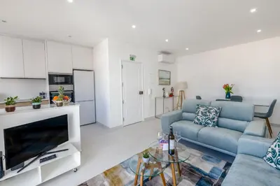 a living room with a blue couch and a tv at The Look-Out Sagres in Sagres