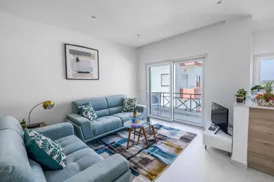 a living room with a blue couch and a tv at The Look-Out Sagres in Sagres