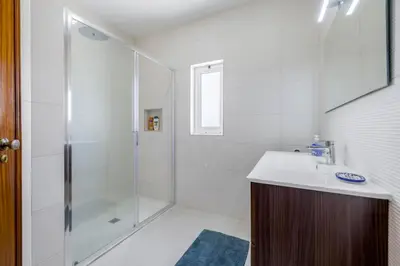 a white bathroom with a shower and a sink at Sunny Sagres in Sagres