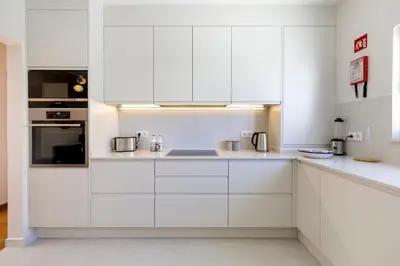 a white kitchen with white cabinets and appliances at Sunny Sagres in Sagres