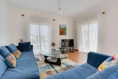a living room with a blue couch and a glass table at Sunny Sagres in Sagres