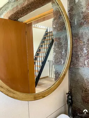 a mirror in a bathroom with a staircase in the background at Raposeira Country House in Calheta