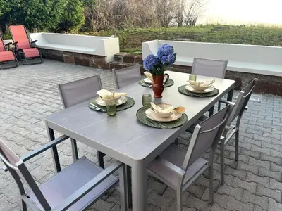 a table and chairs on a patio with flowers on it at Raposeira Country House in Calheta