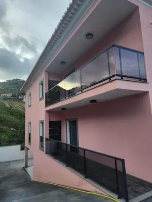 a pink building with a balcony on the side at Peaceful Valley house in Câmara de Lobos
