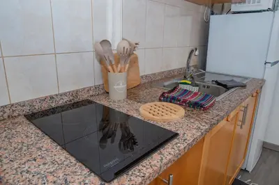 a kitchen with a white refrigerator and wooden cabinets at Sunset Star II With Sea View in Calheta