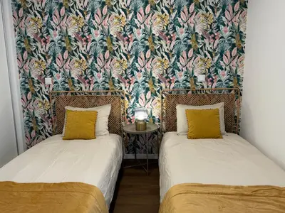 two beds in a room with a floral wallpaper at Stay In Virtudes I in Funchal