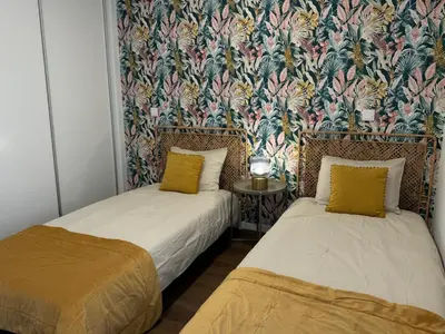 two beds in a room with a floral wallpaper at Stay In Virtudes I in Funchal
