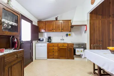 a kitchen with wooden cabinets and a white appliance at Beautiful house in Costa Vicentina in Chabouco
