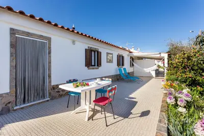 a patio with a table and chairs and a house at Beautiful house in Costa Vicentina in Chabouco