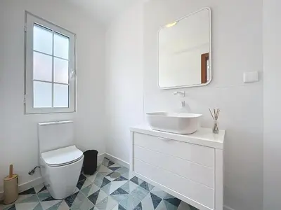 a white bathroom with a sink and a mirror at Moradia Uriel in Santa Cruz