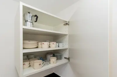 a cupboard filled with white cups and plates at Casa das Malvas in Porto Santo