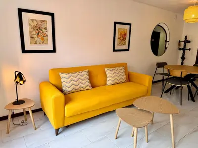 a yellow couch in a living room with tables at Falesia Gardens in Caniço