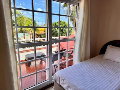 a bedroom with a bed and a view of a balcony at Falesia Gardens in Caniço