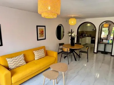 a living room with a yellow couch and a table at Falesia Gardens in Caniço