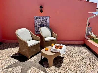a patio with two chairs and a table with food on it at Falesia Gardens in Caniço