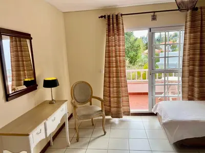 a bedroom with a bed and a desk and a window at Falesia Gardens in Caniço