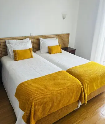 a bedroom with a large bed with yellow blankets and pillows at SOLMAR - Alojamento in Porto Moniz