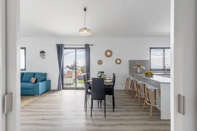 a kitchen and dining room with a table and a blue couch at Maylily Seascape Villa in Santa Cruz