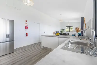 a kitchen with white cabinets and a stainless steel sink at Maylily Seascape Villa in Santa Cruz
