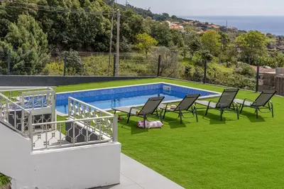 a view of a swimming pool with chairs and grass at Maylily Seascape Villa in Santa Cruz