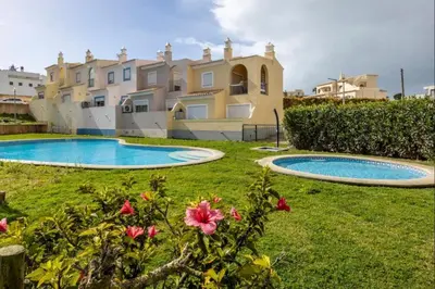 a villa with a swimming pool in front of a house at Casa Cláudia - Cond Atalaia in Lagos