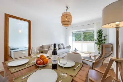a living room with a table with a bottle of wine at Casa Cláudia - Cond Atalaia in Lagos
