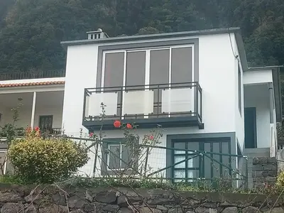 two chairs and a table in front of a red curtain at Lombada Villa Comfort in Ponta Delgada