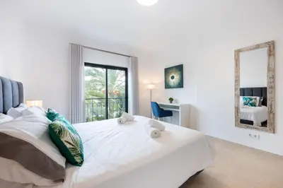 a white bedroom with a large bed and a mirror at Apartment República in Lagos
