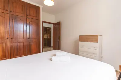 a bedroom with a large white bed with wooden cabinets at Familia Teixeira House by AH in Arco da Calheta