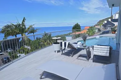 a balcony with a view of a pool and the ocean at Ocean escape with private pool in Arco da Calheta