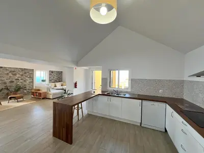a kitchen with a counter top and a living room at Refúgio do Ilhéu in Porto Moniz
