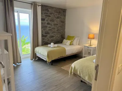 a bedroom with two beds and a view of the ocean at Refúgio do Ilhéu in Porto Moniz