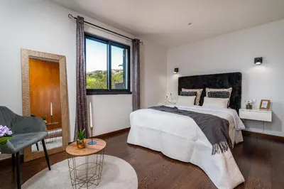 a white bedroom with a large bed and a window at Melblue in Estreito da Calheta