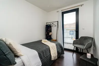 a bedroom with a bed and a chair and a window at Melblue in Estreito da Calheta