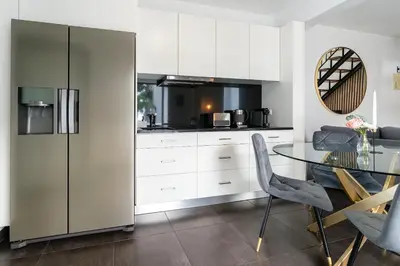 a kitchen with a glass table and white cabinets at Melblue in Estreito da Calheta