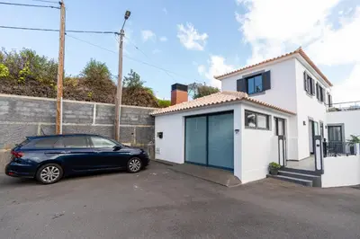 a car parked in front of a white house at Melblue in Estreito da Calheta