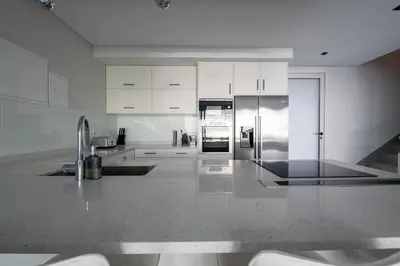 a kitchen with white cabinets and a stainless steel refrigerator at Villa Pérola in Calheta