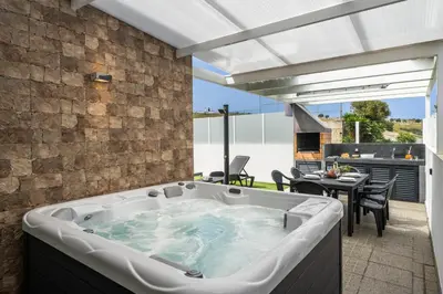 a kitchen with white cabinets and bar stools at OurMadeira - Vila Diana in Porto Santo