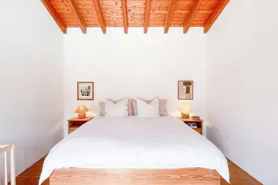a white bedroom with a white bed and two lamps at Casa de Pinheiro in Aljezur
