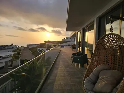 a balcony with a chair and a view of the sunset at Villa Serenity in Prazeres