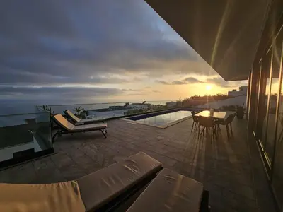 a balcony with a view of the ocean at sunset at Villa Serenity in Prazeres