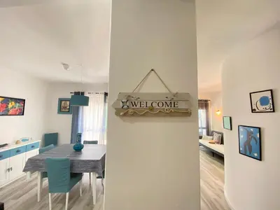 a kitchen and dining room with a table and a welcome sign at NEW Luztur apartment 3min from Luz Beach in Luz
