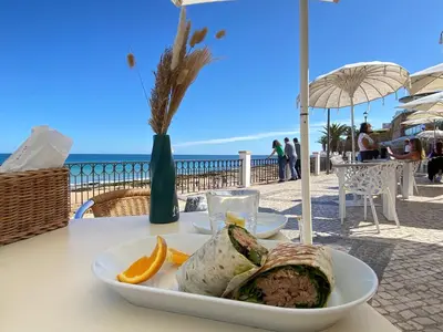 a plate of food on a table next to the ocean at NEW Luztur apartment 3min from Luz Beach in Luz