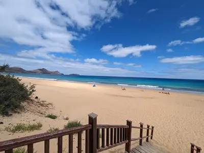 a view of a beach with a wooden bench at Apartamentos Aurea - Porto Santo in Porto Santo