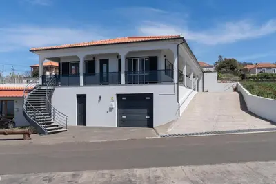 a large white house with a staircase in front of it at Paul's Holiday House in Ponta do Pargo