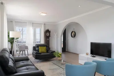 a living room with black leather furniture and a tv at Paul's Holiday House in Ponta do Pargo