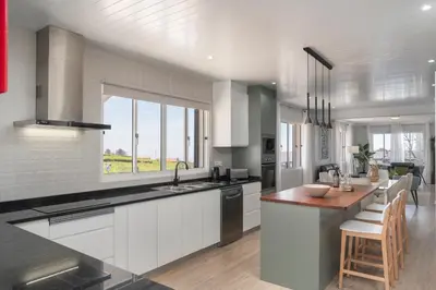a kitchen with white cabinets and a large window at Paul's Holiday House in Ponta do Pargo