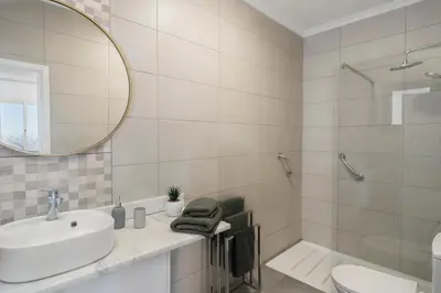a white bathroom with a sink and a mirror at Paul's Holiday House in Ponta do Pargo