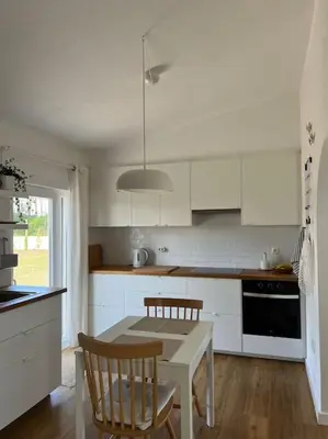 a kitchen with white cabinets and a table and chairs at Casa de Maio - New T2 - ARRIFANA BEACH 650 mts in Aljezur