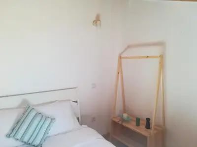 a bed with a blue pillow and a wooden table at Studio Rufia in Vila do Bispo